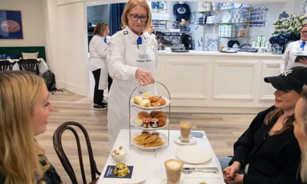 A member of the waiting staff places food on the table on a silver afternoon tea stand