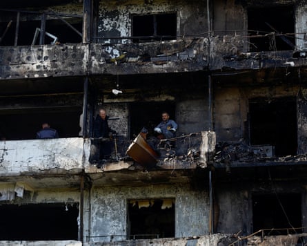 Residents throw away broken furniture from a balcony of an apartment of a residential building.