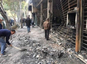 Iranians walk past a charred bank that was set ablaze during a demonstration in the central city of Isfahan.