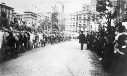Crowds watch soldiers on horseback