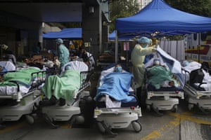 Patients lie on hospital beds as they wait at a temporary makeshift treatment area outside Caritas Medical Centre on Friday 18 February. Hong Kong’s hospitals reached 90% capacity on Thursday and quarantine facilities were at their limit, authorities said, as the city struggles to snuff out a record number of new Covid cases by adhering to China’s “zero tolerance” strategy.