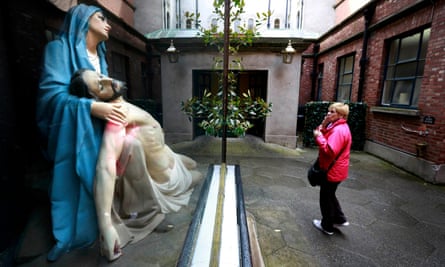 A woman prays in front of a statue of Mary and Jesus in the Grafton street area of Dublin.