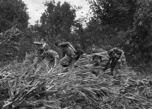 Life magazine photographer Larry Burrows (far left) struggles through elephant grass and the rotor wash of an American evacuation helicopter as he helps GIs carry a wounded soldier on a stretcher from the jungle to the chopper in Mimot, Cambodia, May 4, 1970