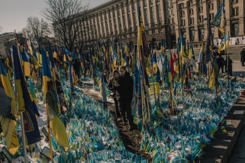 People stand amid flags erected in the square