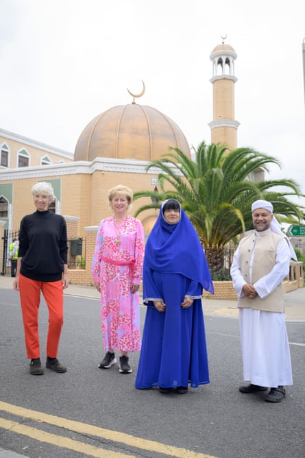 Four people standing outside a mosque, smiling at the camera