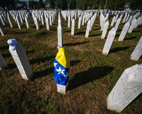A gravestone is covered with the flag of Bosnia and Herzegovina at the memorial cemetery in the village of Potocari, near the eastern Bosnian town of Srebrenica on the 30th anniversary of the Srebrenica massacre.