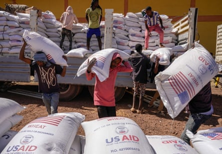 People unloading large sacks of flour from a truck