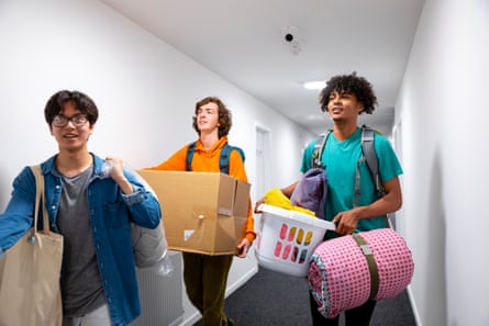 Three young male students carrying their belongings and walking to their new rooms in their student accommodation