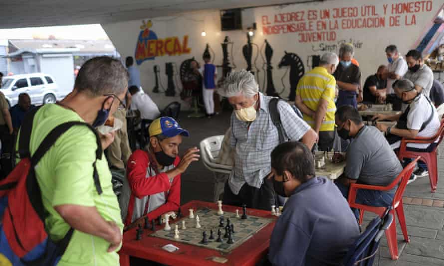 Men wearing masks play chess under a bridge in Caracas, Venezuela, Saturday, Dec. 26, 2020, amid the coronavirus pandemic.