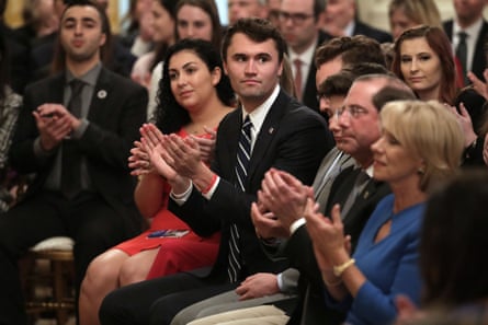 A young man claps in a room full of seated people