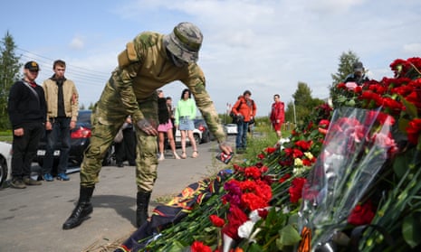 A man wearing military camouflage adds a tribute to a row of flowers