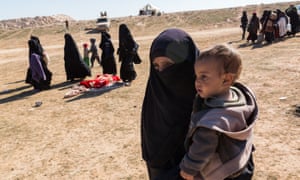 A woman holding a child arrives at a civilian collection point for suspected Isis families
