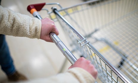 A shopper holds a supermarket trolley's bar fitted with a row of lights