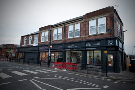 A small row of single-storey shops with redbrick flats above them
