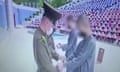 Still from a video, made by North Korean authorities, showing a large public trial in which the two students in grey scrubs are handcuffed while watched by about 1,000 students in an amphitheatre.