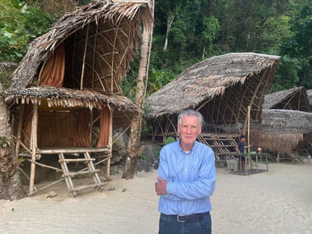 Michael Palin by a simple two-story structure built of bamboo and coconut palm fronds