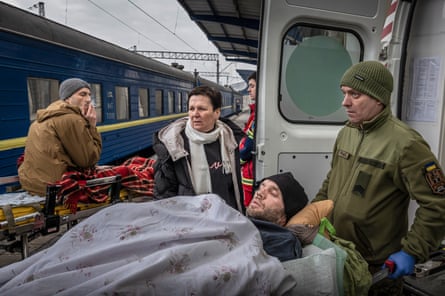 Wounded man in a stretcher is being wheeled on to a train