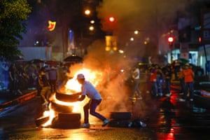 A protester piles burning tyres in a road as other demonstrators look on