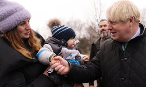 Boris Johnson shakes hands with Sun Kuzma, fourteen months, as his mother Olga, 33, holds him during a visit to the Church of Saint Apostle Andrew the First-Called in Bucha.