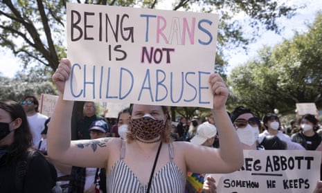 A woman holds a sign at a rally that reads "Being trans is not child abuse".