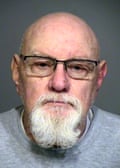 An older bald man with a gray goatee.