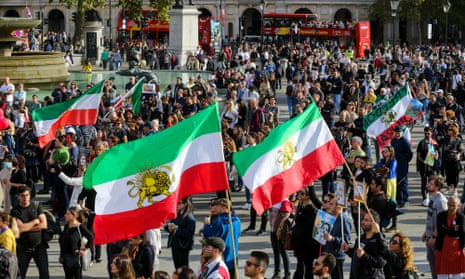 Protesters wave Iranian flags and stand in an open space next to a fountain in London