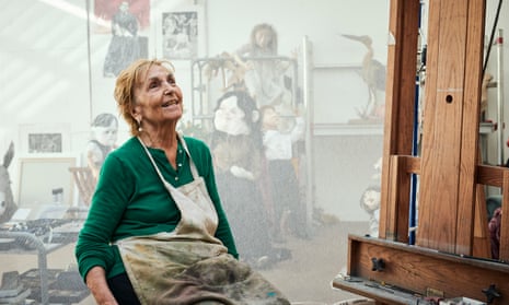 Paula Rego in her studio wearing a paint-spattered apron and smiling