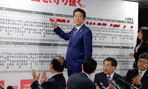 Japanese Prime Minister Shinzo Abe puts a red rose on name of a party's candidate to be elected in the lower house election.