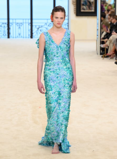 A model in a V-neck sleeveless long dress made of green and turquoise sequins
