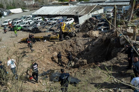 प्रथम प्रतिक्रियाकर्ता इज़राइल के बेइत शेमेश में एक ईरानी मिसाइल द्वारा छोड़े गए गड्ढे के पास इकट्ठा होते हैं।