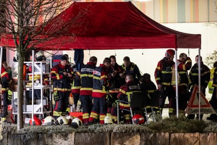 Firefighters stand under a tent at night