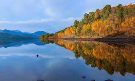 Blue loch with autumn trees reflected in water