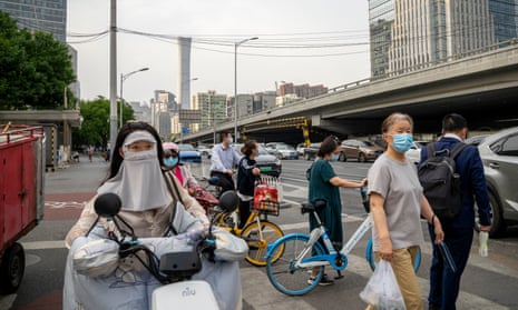 Commuters wear masks against Covid as they wait to cross a road in the centre of Beijing on Thursday