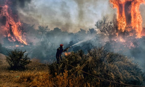 A firefighter douses flames on a wildfire at the Panorama settlement near Agioi Theodori, about 70km west of Athens, on 18 July 2023.