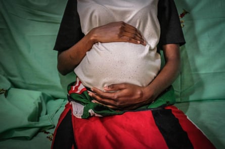 A pregnant teenager, seen from shoulder to waist, in Kibera slum, Nairobi, Kenya.