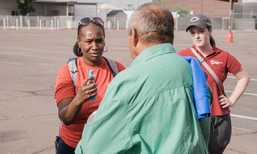 Volunteer Lillie Long, left, and AmeriCorp Vista worker Emily Shiels talk to a man while giving him a demonstration of a portable mister.