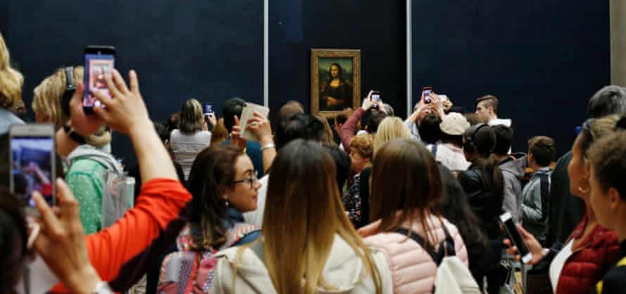 Smile, please … tourists take snaps of the Mona Lisa at the Louvre.