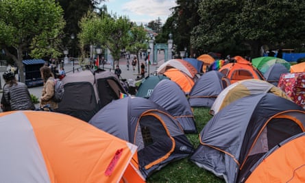 Orange, blue, green and gray tent tops among trees.