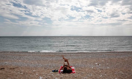 Getting away from it all … a man reads a book at a beach in Glyfada, a suburb of Athens.