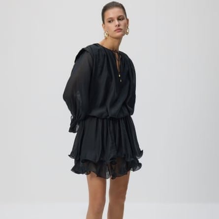 A model wears a short black v-neck dress with tie details