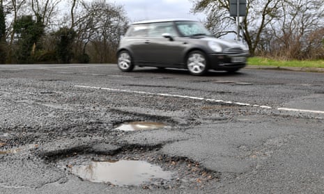 Picture of a car driving pass potholes full of water.