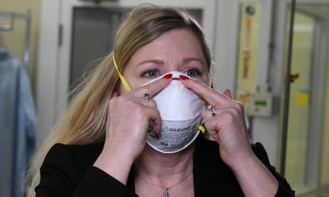 Nicole McCullough, a global health and safety expert at 3M, demonstrates the correct way to put on a N95 respiratory mask at a laboratory of 3M in Maplewood, Minnesota.