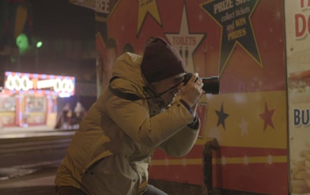 Polly Braden dressed in cold-weather clothes indoors, taking photographs in Blackpool