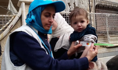 A Unicef employee measures the arm of a malnourished child in the besieged Syrian town of Madaya.