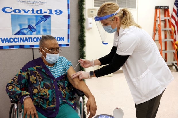 A female medical worker gives a vaccine to an elderly woman in a wheelchair. 