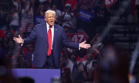 a man in a blue suit and red tie speaks with his hands outstretched