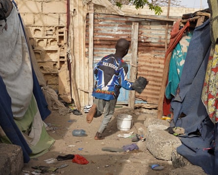 A boy running in an alley between shacks