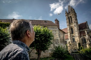 Philippe Vieillard looks at a plane flying over the church