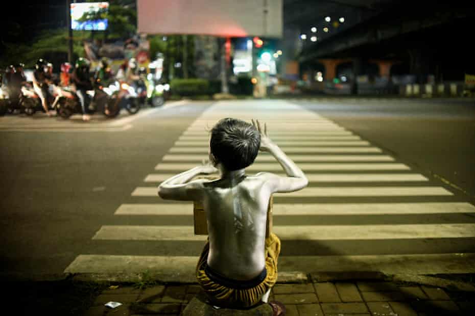 A child wearing silver paint on their body, also known as a ‘silverman’, begging for money in Jakarta.