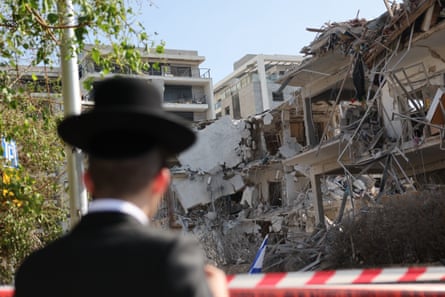 A person stands near a damaged residential building after a ballistic missile strike in Tel Aviv.